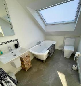 ein Badezimmer mit einer Badewanne, einem Waschbecken und einem Dachfenster in der Unterkunft Stunning 2 bed apartment in Jesmond in High Heaton