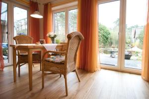 uma sala de jantar com mesa, cadeiras e janelas em Adelheid Winkelmann em Hermannsburg