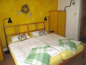 Cama grande en habitación con pared amarilla en Atelier am Markt en Hermannsburg