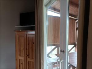 a door to a balcony with a tv and a window at La Masia BG parc in Sant Pere Pescador