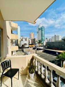 a balcony with a chair and a view of a city at Ótima localização quadra mar e central in Balneário Camboriú