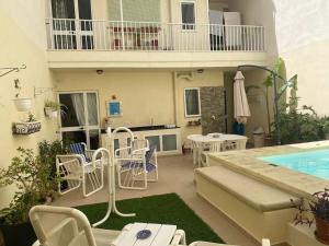 une terrasse avec des chaises blanches et une piscine dans l'établissement The Valley Maisonette with private pool in M'scala, à Marsaskala