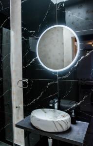 a bathroom with a round mirror on a black wall at Apartmani DA in Piran