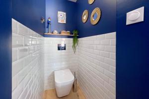 a bathroom with a toilet and a blue wall at Appart 2 personnes à 50m des commerces & mer in Barneville-Carteret +27 photos
