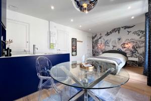 a dining room with a glass table and a bed at Appart 2 personnes à 50m des commerces & mer in Barneville-Carteret
