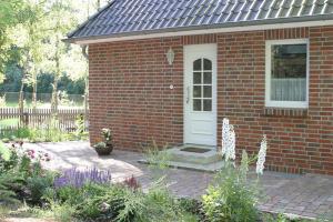 a red brick house with a white door at Ferienwohnung Am Hasenberg in Hermannsburg