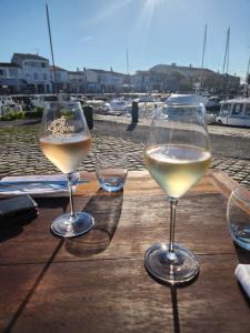 twee glazen witte wijn zittend op een houten tafel bij Côté Ré in Saint-Martin-de-Ré