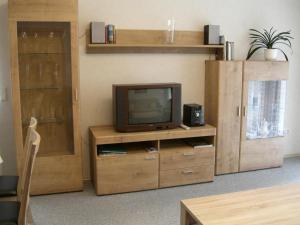 a living room with a tv on a wooden entertainment center at Ferienwohnung Am Hasenberg in Hermannsburg