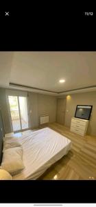 a bedroom with a large white bed and a flat screen tv at Jijel in Oum el Bouaghi