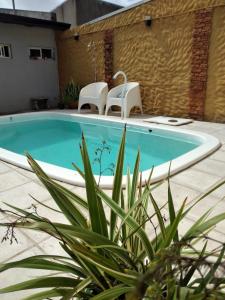 una piscina con 2 sillas blancas al lado en Alojamiento Turístico Los Pinos en Villa Elisa