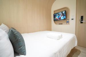 Schlafzimmer mit einem weißen Bett und einem TV an der Wand in der Unterkunft W 21 Hotel Bangkok in Bangkok