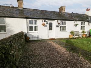 una casa blanca con una pared de piedra delante de ella en Bwthyn Taid a Nain, en Bodorgan