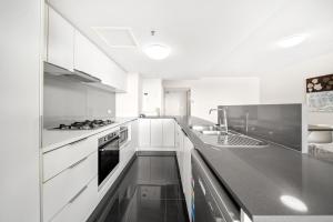 uma cozinha com armários brancos e um balcão preto em Oxygen Apartments em Brisbane