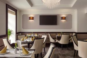 een restaurant met tafels en stoelen en een flatscreen-tv bij Boutique Hotel Saxonia in Karlsbad