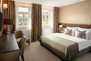 a hotel room with a bed and a chair at Boutique Hotel Saxonia in Karlovy Vary