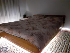 Una cama en un dormitorio con una manta. en Pantića avlija - Ethno household en Požega
