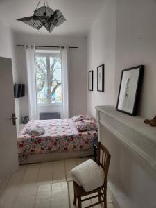 a bedroom with a bed and a chair and a window at Maison Laurenza/ La Liversoise in Saint-Jean-de-Liversay