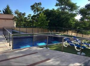 a swimming pool with two chairs and a fence at LOFT BETANIA in Cáceres
