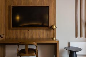 a desk with a television on a wall with a chair at Hôtel-Musée Premières Nations in Wendake