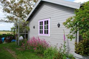 a white house with a pink window and some flowers at B&B Öland in Ottoland