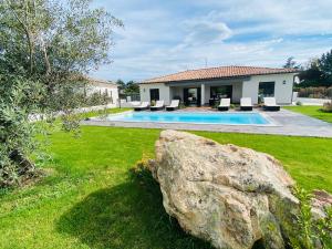 una casa con piscina y una roca grande en Capella Suttana, en Ventiseri