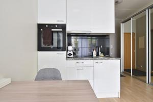 a kitchen with white cabinets and a chair in it at Stylish Studio with Free Private Parking & Wi-Fi in Tallinn