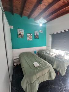 a bedroom with two beds and a green wall at Sol y Luna B&B in Monte Grande