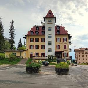 a large white building with a red roof at Hotel Regina del Bosco in Ronzone