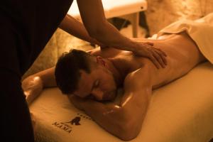 Un uomo sdraiato su un letto che si fa fare un massaggio di Sei Stelle Mama a Polignano a Mare