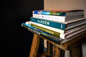 una pila de libros sobre una mesa de madera en Bed and Breakfast Waddendroom, en Lioessens