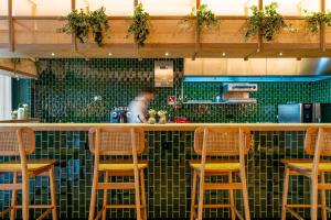 a bar with wooden stools in a kitchen with green tiles at The Editory Garden Porto Hotel in Porto +48 photos