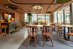 a restaurant with wooden tables and chairs and windows at The Editory Garden Porto Hotel in Porto