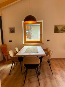 a dining room table with chairs and a window at Casa Marta Dolomiti in Vigo di Fassa