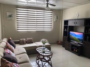 a living room with a couch and a tv at Casa en Ballenita: Piscina, Vóley, BBQ y Mar Cerca in Ballenita