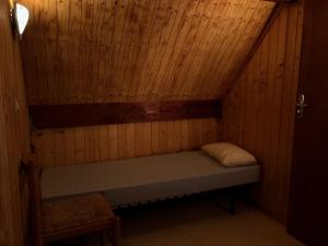 een kleine kamer met een bed in een houten muur bij Chalet dans le parc d'un manoir du XIXème in Anglès