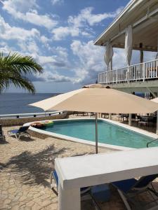 a pool with an umbrella next to the ocean at Begona Cliff Hotel in Negril