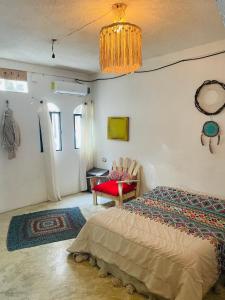 a bedroom with a bed and a chair and a chandelier at Casa Iguana in Isla Mujeres