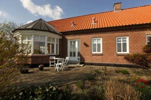 a brick house with a table and chairs on a patio at Løftgård Bed and Bath in Ovtrup