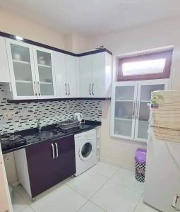 a kitchen with white cabinets and a washing machine at sea and mountain view roof terrace central in Alanya