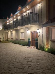 a building with a balcony and a courtyard at night at Pousada Ville Le Mont in Campos do Jordão