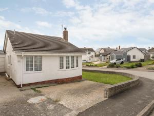 a white house with a driveway in a residential neighborhood at 31 Sisial Y Mor in Rhosneigr