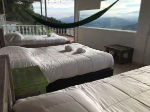 a room with three beds and a balcony with a view at La Casa de la Montaña in La Vega