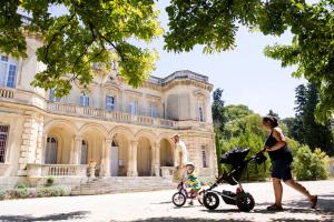 Una donna che spinge un bambino in un passeggino davanti a un palazzo di Huttopia Fontvieille a Fontvieille