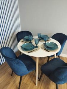a table with blue chairs and a white table with plates at Apartament blisko stacji kolejowej in Mińsk Mazowiecki