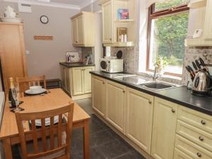 a kitchen with wooden cabinets and a table and a sink at Swn Y Nant in Tondu