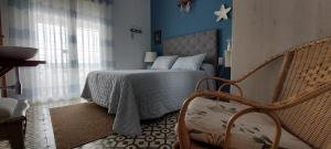 a bedroom with a bed with blue walls and a chair at Montserrat Casa del Mar in Chipiona