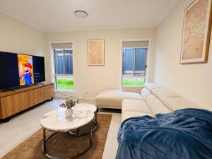 un soggiorno con divano e TV di Brand new fancy house in the heart of Leppington a Horningsea Park