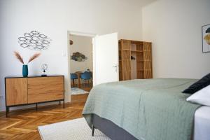 ein Schlafzimmer mit einem Bett und einer Holzkommode in der Unterkunft Trendy Apartment 3 Zimmer zentral gelegen in Wien