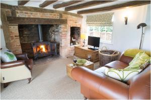 a living room with a couch and a fireplace at The Cottage, High Ash Farm in Peasenhall