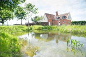 a body of water in front of a house at The Cottage, High Ash Farm in Peasenhall